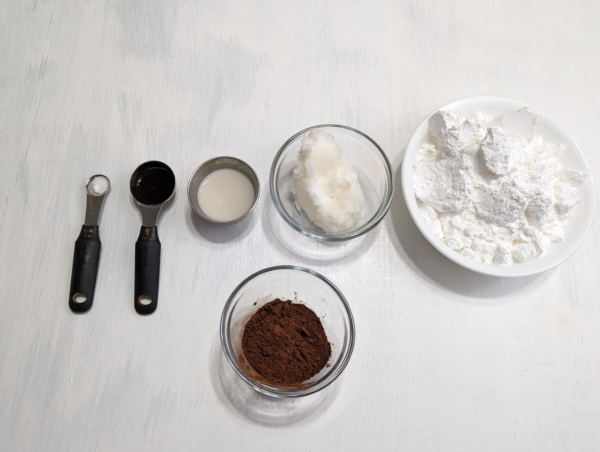 An image of the frosting ingredients; salt, vanilla, almond milk, cocoa powder, coconut oil, and powdered sugar