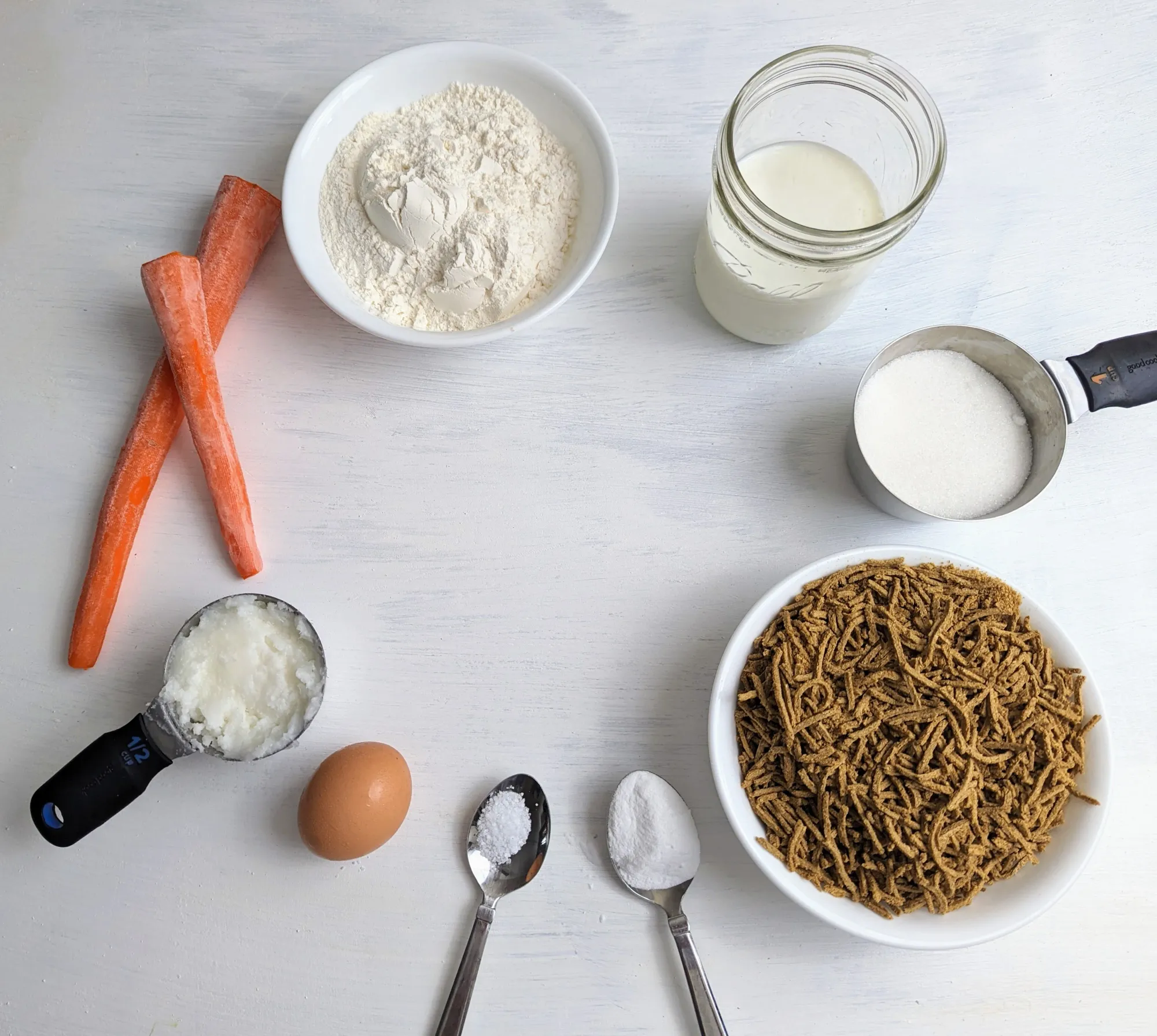An image of all the ingredients; bran, coconut oil, eggs, buttermilk, sugar, flour, baking soda, salt and carrots