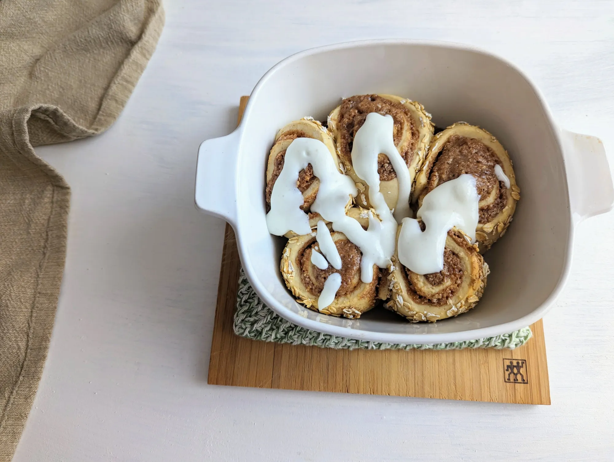 5 cinnamon rolls in a dish covered with a creamy white frosting