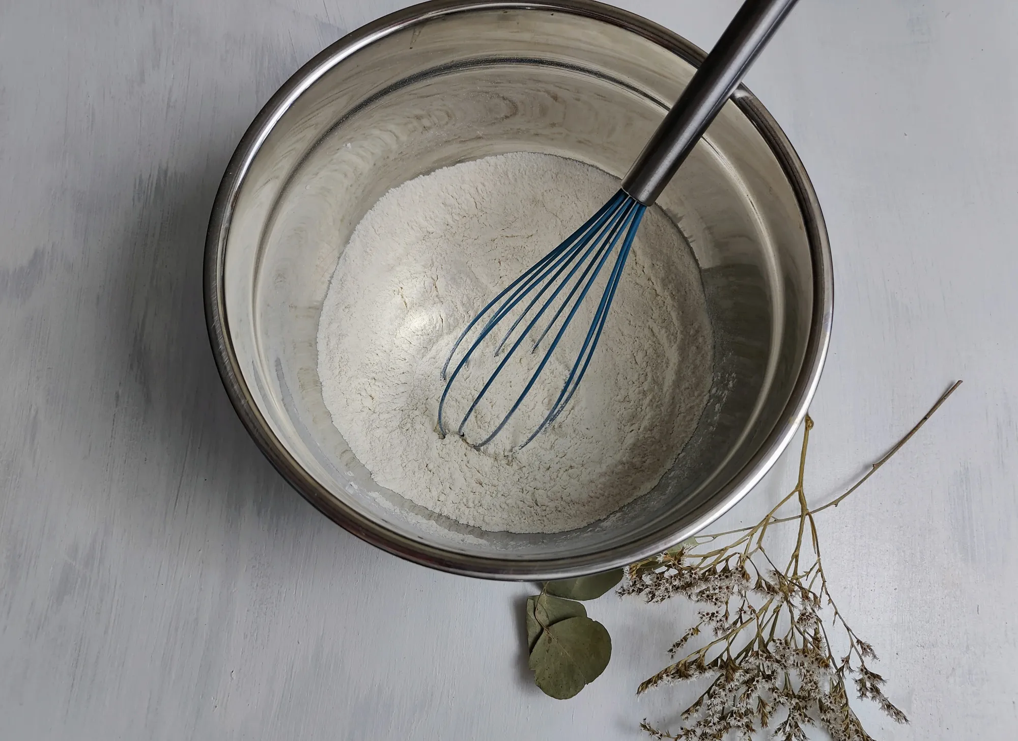 A bowl of flour, with a whisk