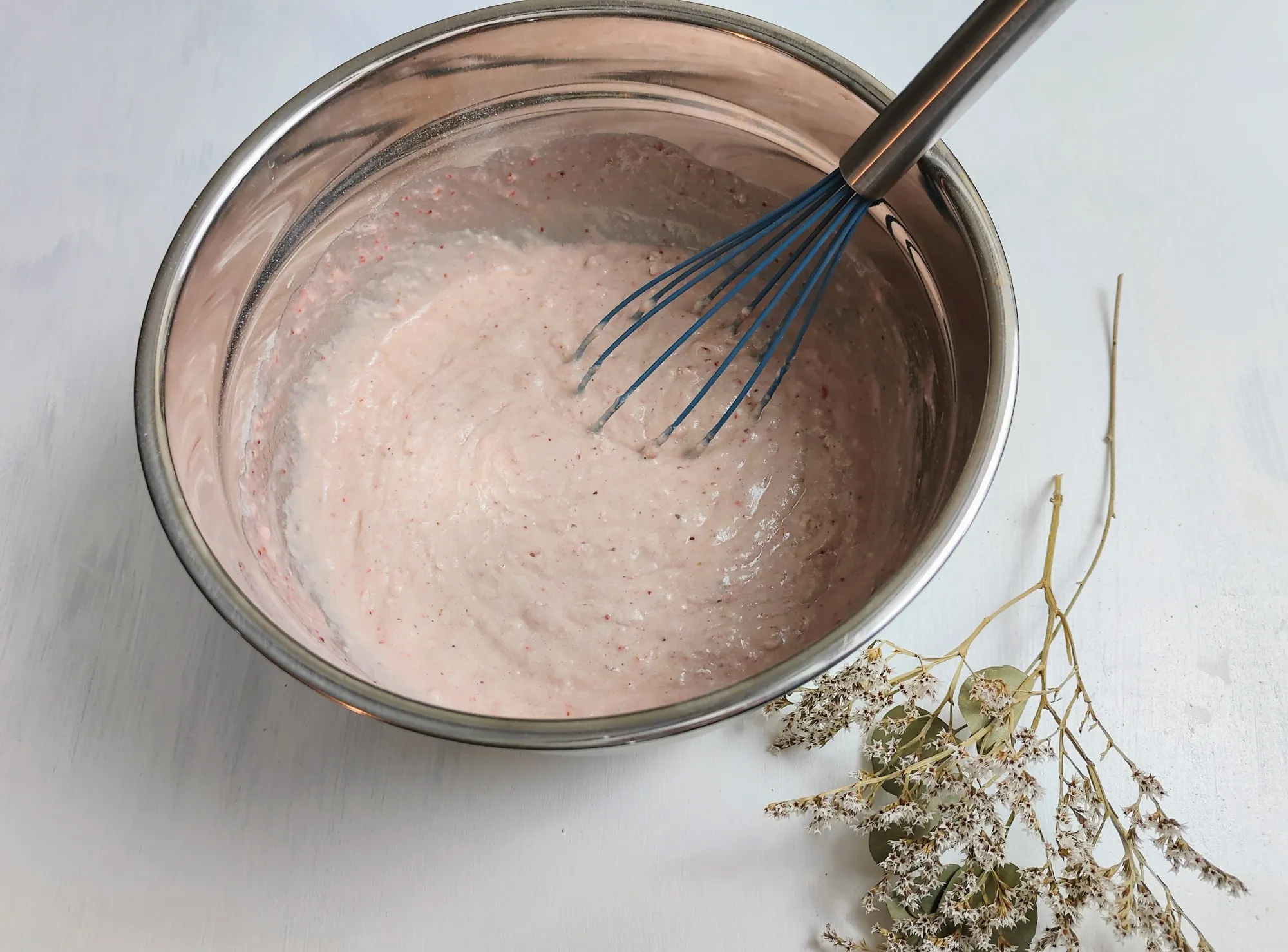 A bowl of pink batter with a whisk