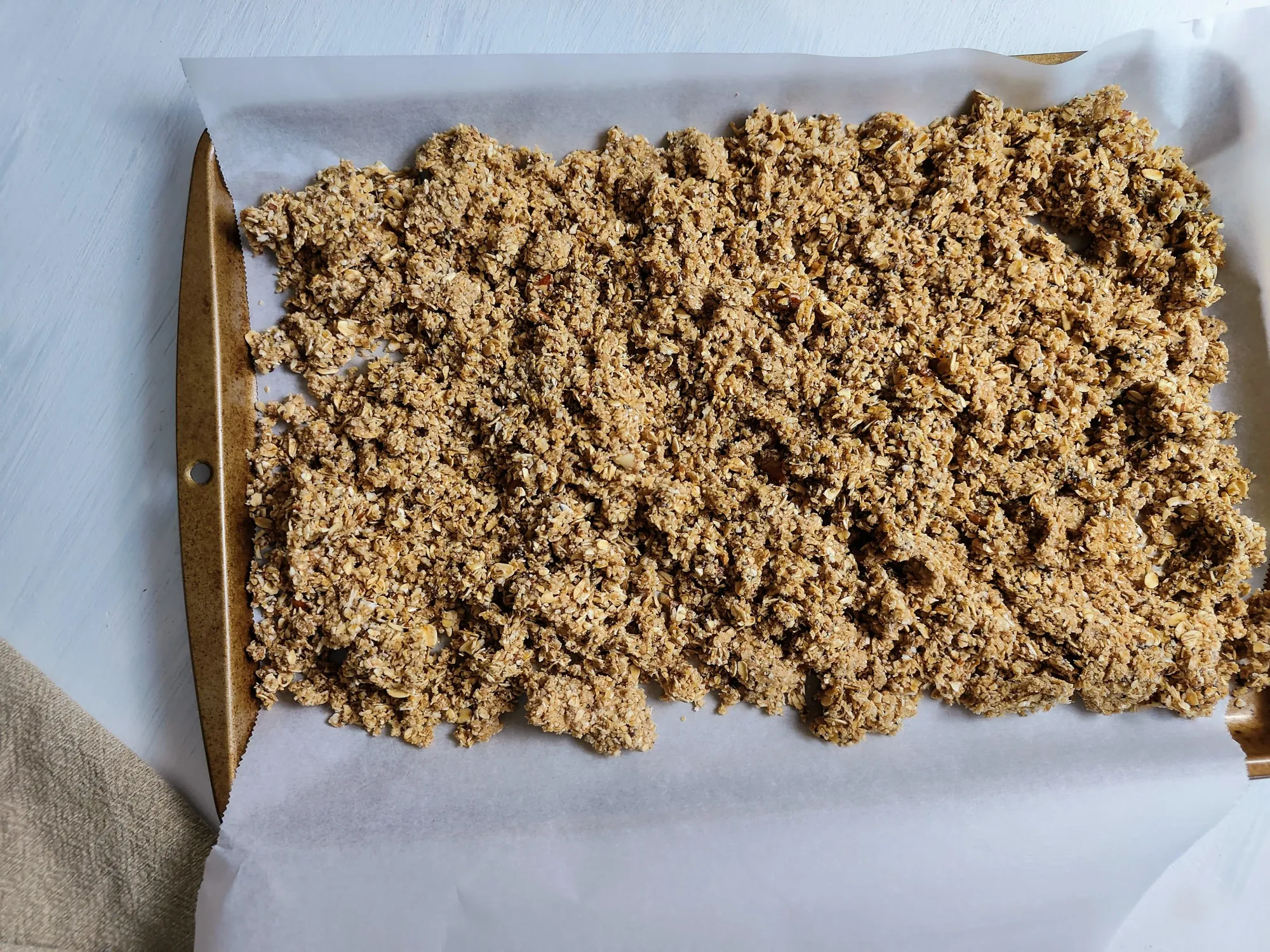 Granola spread out on a parchment sheet