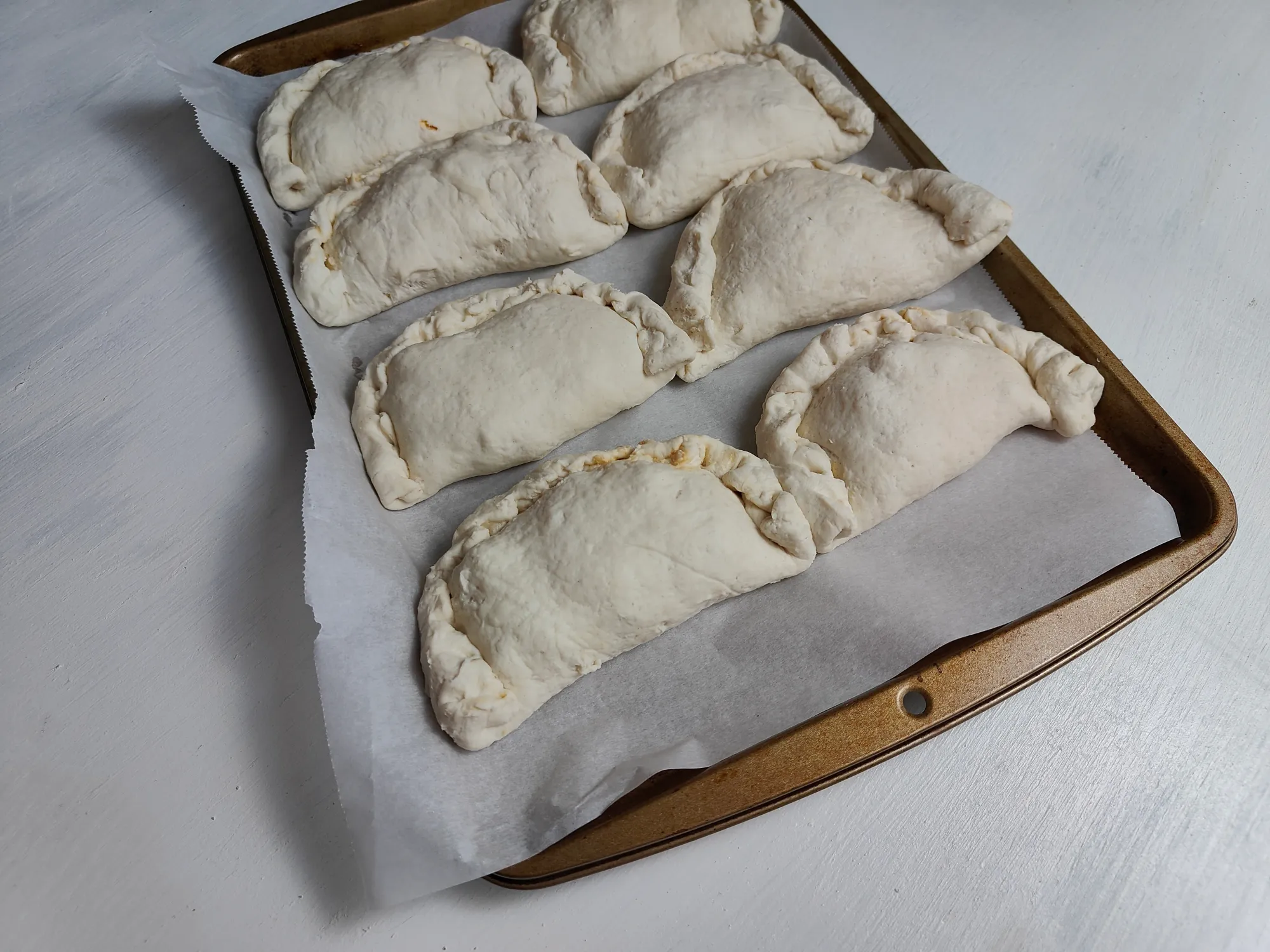 Unbaked calzones on a baking sheet