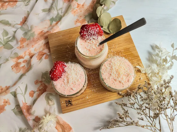 Overnight oats in glass jars topped with shaved white chocolate and strawberries